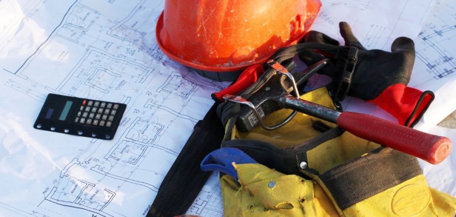 Baustelle Bauplan mit Helm und Werkzeug